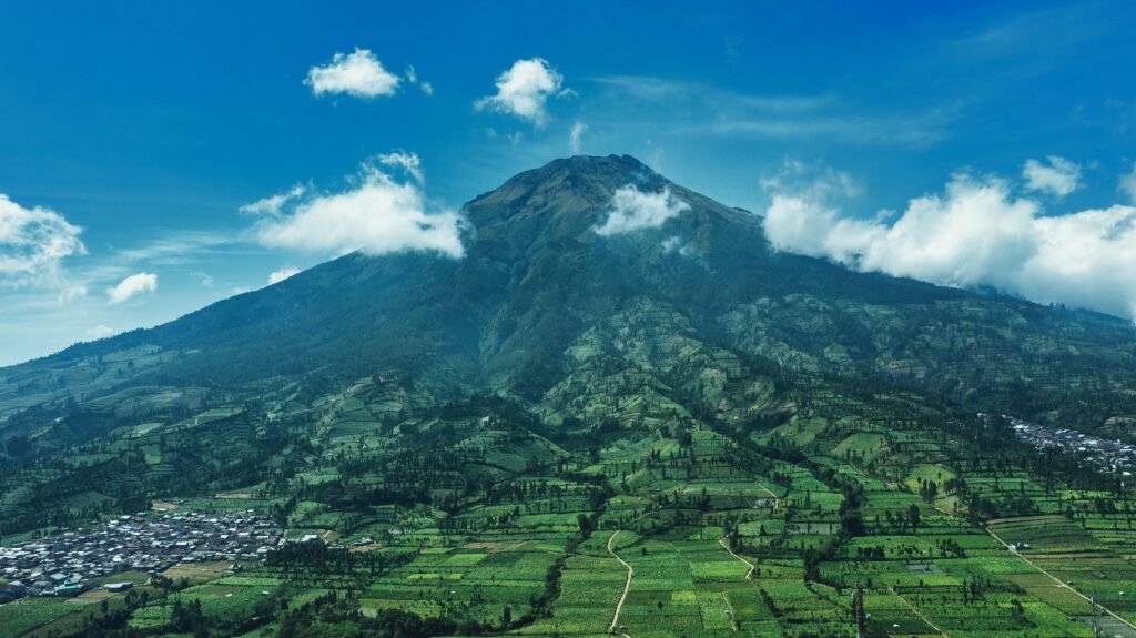 A breathtaking aerial view of Mount Sindoro and lush farmlands in Wonosobo, Central Java, Indonesia.